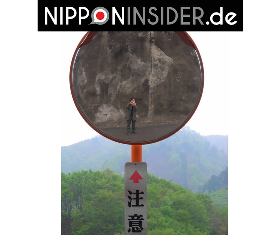 Selbstportrait in den Spiegel fotografiert, Hintergrund: japanische Berglandschaft