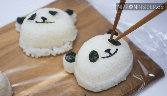 Anbringen von Augen, Ohren, Nase und Mund auf den Reis-Panda-Kopf für die Charaben
